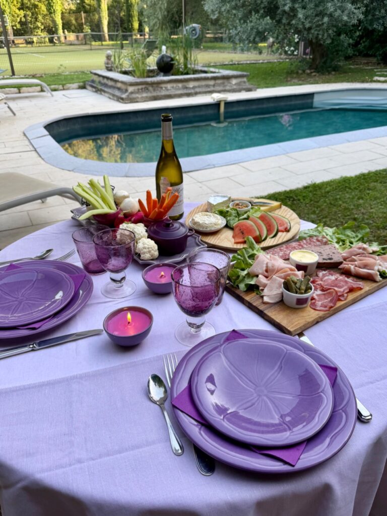 Table élégamment dressée pour un dîner romantique avec charcuterie, fromages, crudités et vin blanc au bord d'une piscine en Provence, au Mas de la Sacristière.